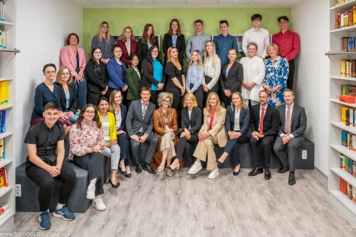Gruppenfoto einer Maturaklasse in festlicher Kleidung vor Bücherregalen