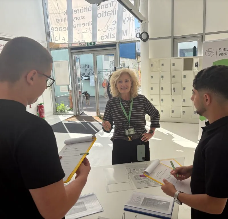 Zwei Schüler arbeiten mit einer Betreuerin an einem Stehtisch in der Ausstellung