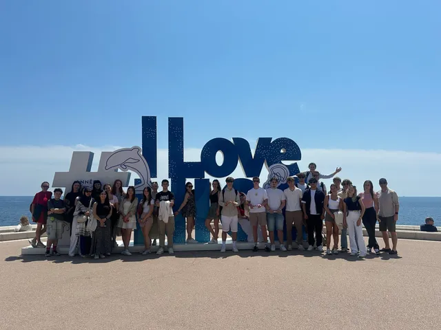 Gruppenfoto der Klasse an einer Strandpromenade vor einem großen Schriftzug
