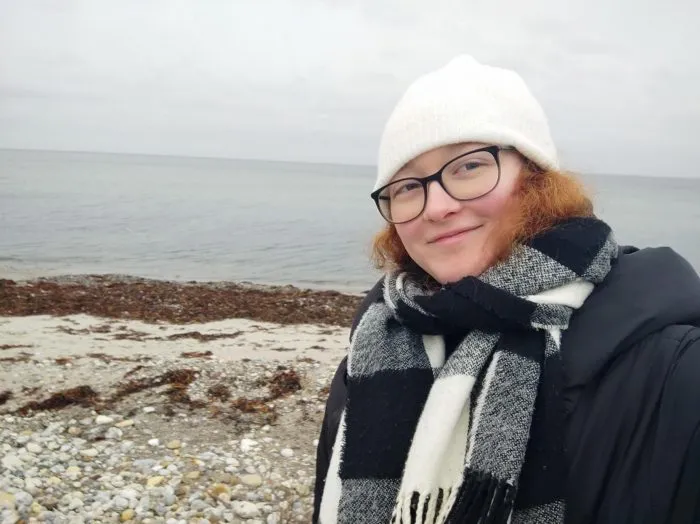 Schülerin mit Mütze und Schal am Strand in Dänemark