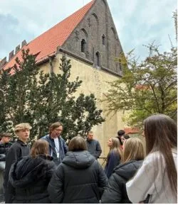 Schülerinnen und Schüler bei einer Führung vor einer gotischen Kirche in Prag