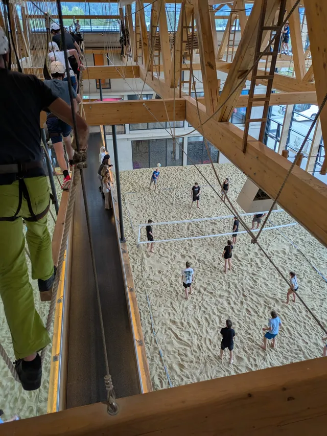Blick von oben in eine Beachvolleyball-Halle, vorne ein Kletterparcours