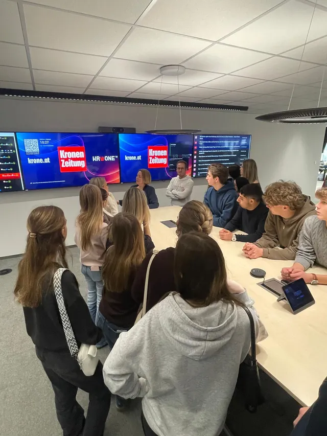 Schülerinnen und Schüler in einem Zeitungs-Newsroom mit Bildschirmwand